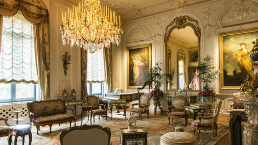 Interior of the Grey Drawing Room at Waddesdon Manor, Buckinghamshire, showing furnishings including chandelier, large mirror, seating and portraits.